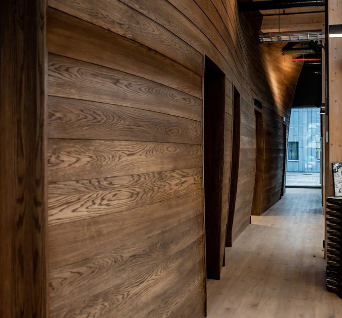 Photo along the wall installation, showing the wave-like form and wooden texture. Photo: Tove Lise Mossestad / Vill Mer