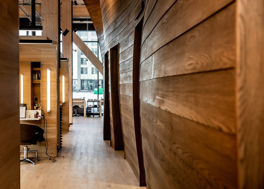 Photo along the wall installation towards the entrance, showing the wave-like form and wooden texture. Photo: Tove Lise Mossestad / Vill Mer