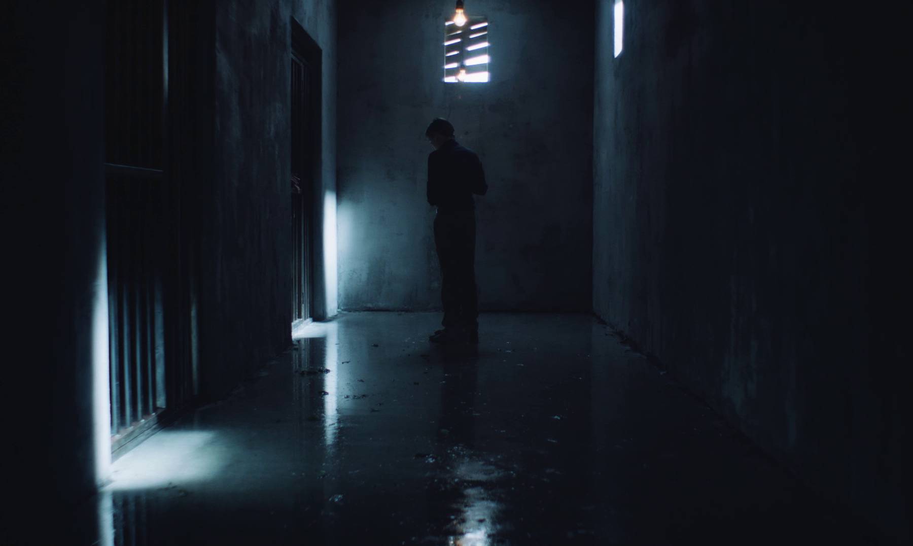 Still image from the movie, showing the main character Jacob sweeping the prison corridor floor.