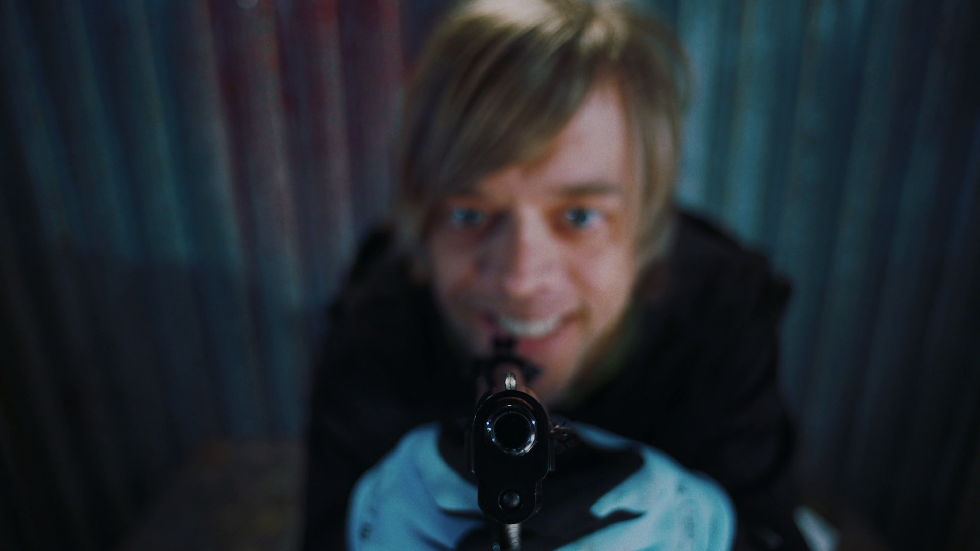 Still from the film showing the main character aiming a gun at the screen.