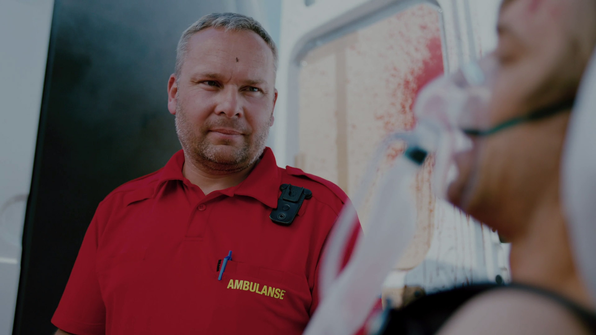 Still from the film showing the an ambulance medic with the fly on his forehead.